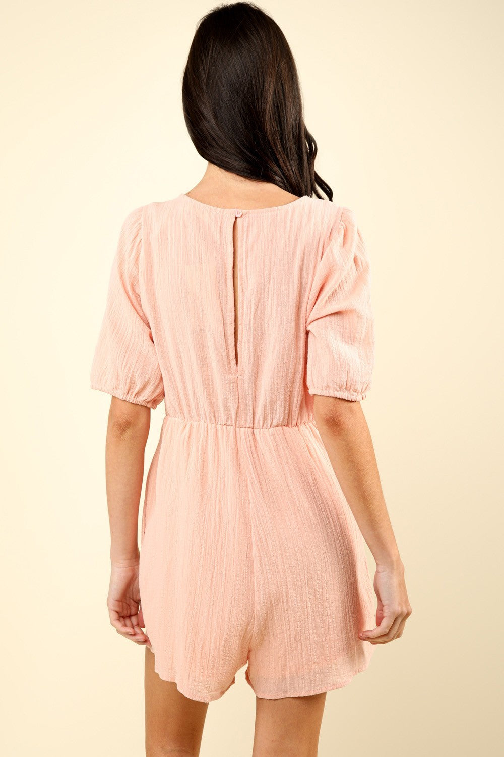 woman wearing pink lace romper back view