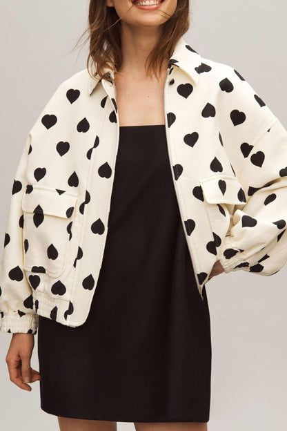 woman wearing ivory light bomber jacket with black hearts on it