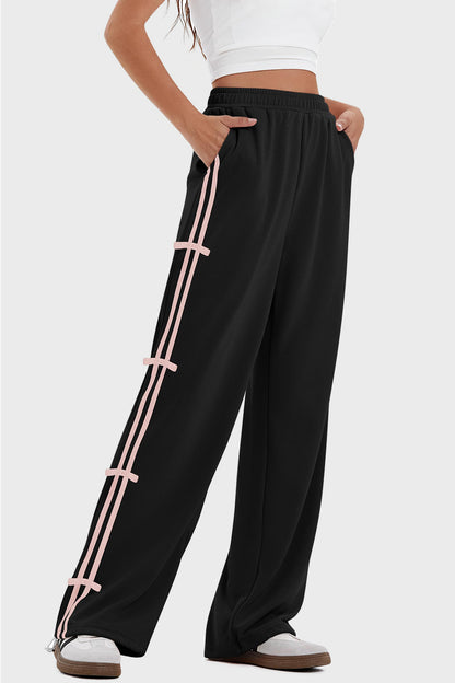 woman wearing bow striped track pants in black with pink