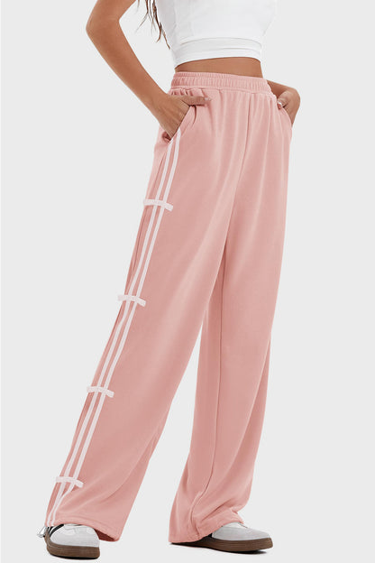 woman wearing bow striped track pants in pink with white