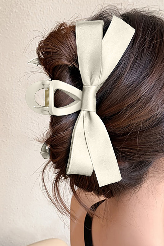 Woman wearing claw clip with bow in ivory in an updo hairstyle