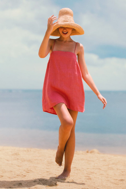 woman wearing the mini resort dress in pink on the beach