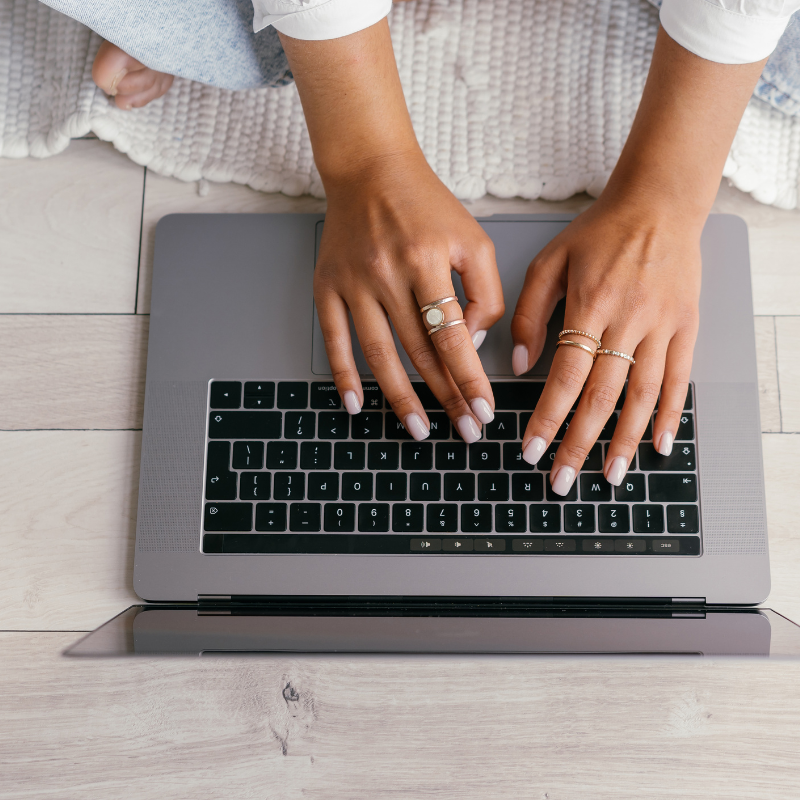 woman's manicured hands typing on laptop