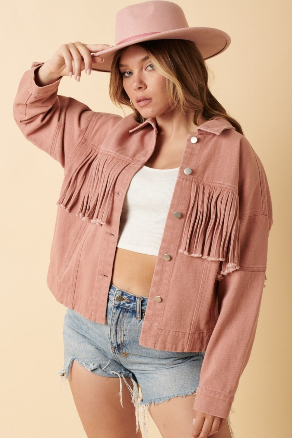 woman wearing western fringe jacket in blush pink and a cowboy hat